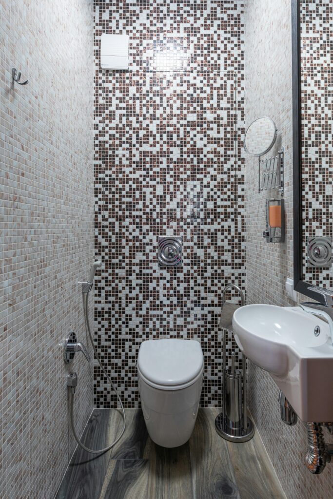 Contemporary bathroom featuring mosaic tile design, sink, and toilet.